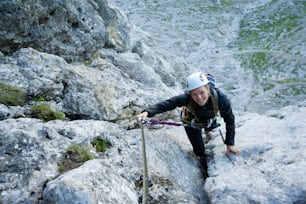 attraente alpinista nelle Dolomiti d'Italia sulla ripida e difficile via ferrata Poessnecker