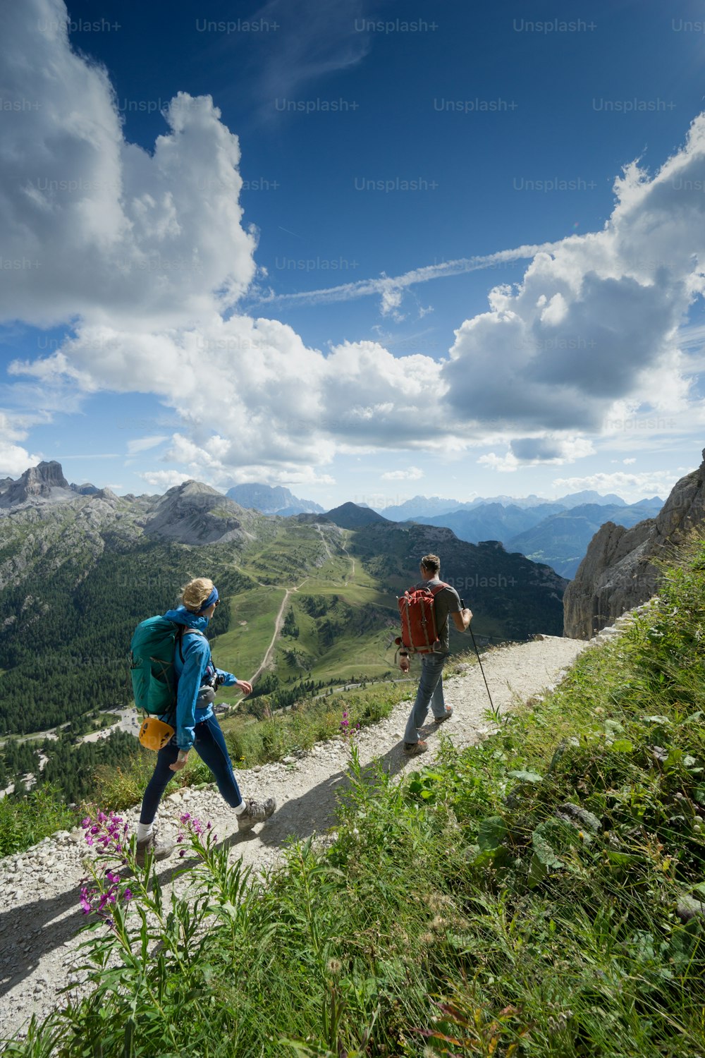 mountain guide and blonde woman client returning from a climb in the Italian Dolomites and hiking down a path