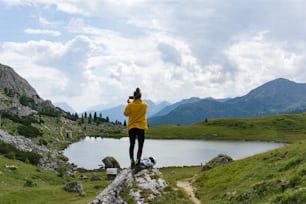 Una alpinista se para sobre una roca y toma fotografías del paisaje en los Dolomitas de Italia con su teléfono celular