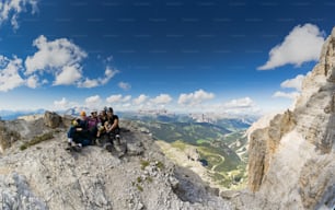 panorama view of four attractive women mountain climbers hug and smile on a mountain peak after a hard climb in the Italian Dolomites near Cortina d'Ampezzo