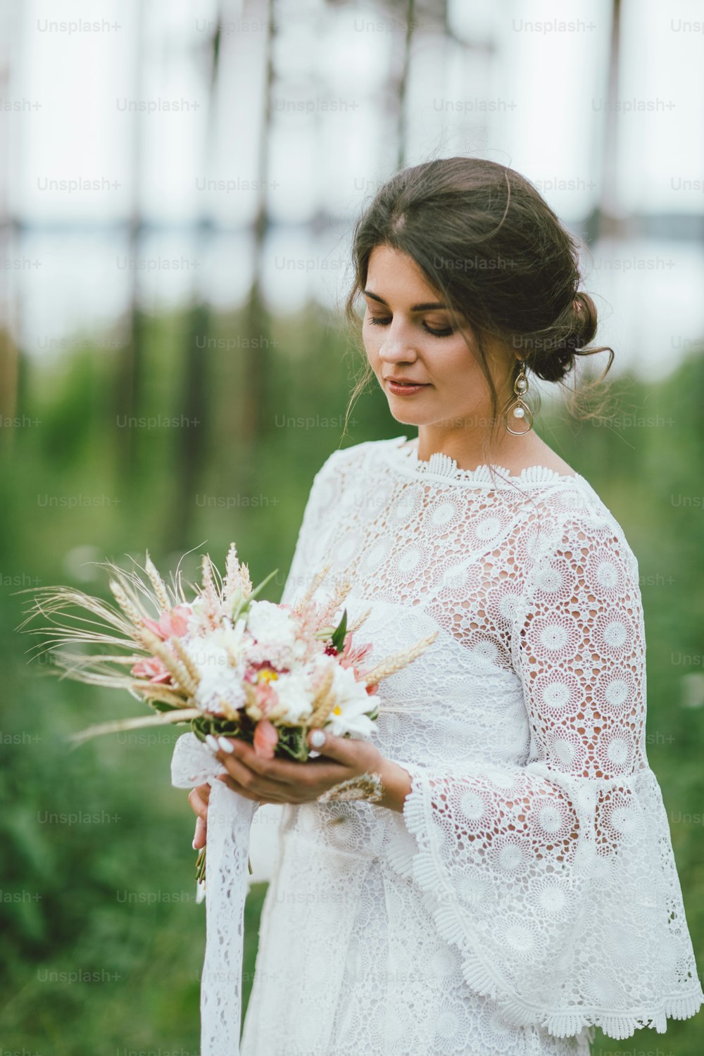 Beautiful smiling bride brunette young woman in white lace dress with wedding boho bouquet, close up portrait outdoors