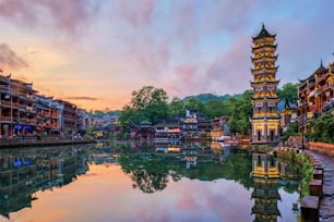 Chinese tourist attraction destination - Feng Huang Ancient Town (Phoenix Ancient Town) on Tuo Jiang River with Wanming Pagoda illuminated at night. Hunan Province, China