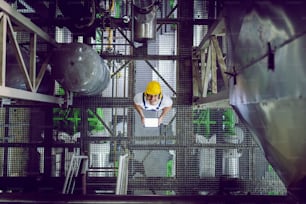 Top view of smiling plant worker in protective clothing using tablet.