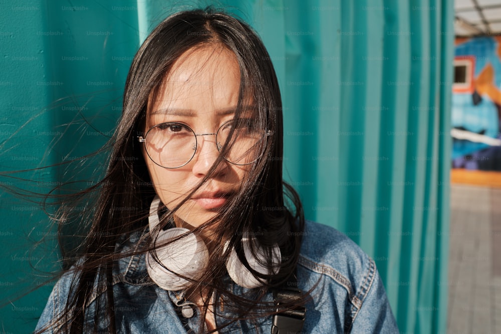 Porträt eines asiatischen Mädchens mit Brille, das direkt in die Kamera schaut.