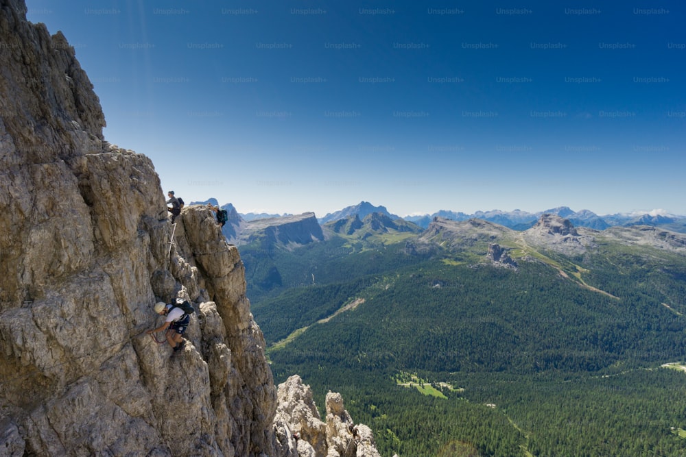 view of a group of climbers on a steep Via Ferrata with a grandiose view of the Italian Dolomites in Alta Badia behind them