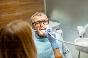 Handsome man as a patient during a teeth inspection with a female dentist at the dental office