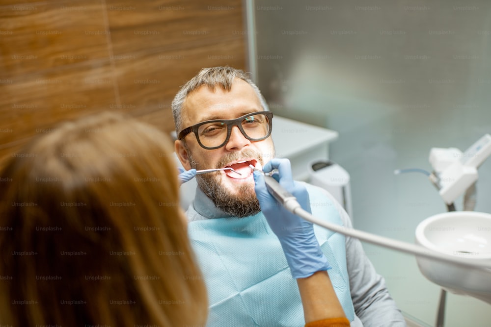Hübscher Mann als Patient bei einer Zahninspektion mit einer Zahnärztin in der Zahnarztpraxis