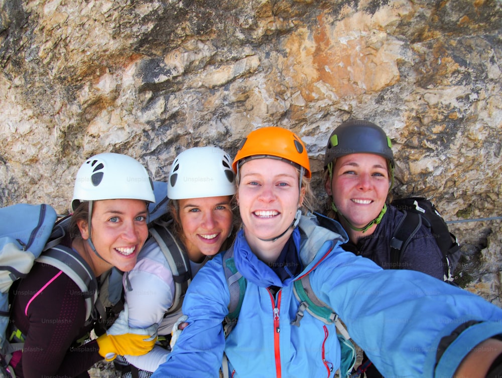 Vue de quatre alpinistes célébrant au sommet de la montagne en prenant une photo de groupe