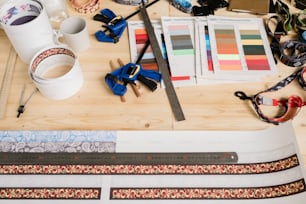 Ruler on paper with set of decor, samples of textile, mug with drink and other stuff for accessory design on wooden table