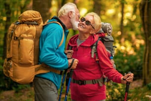 Felice coppia senior sta facendo un'escursione nella foresta. Avventura, viaggio, escursione e concetto di persone.