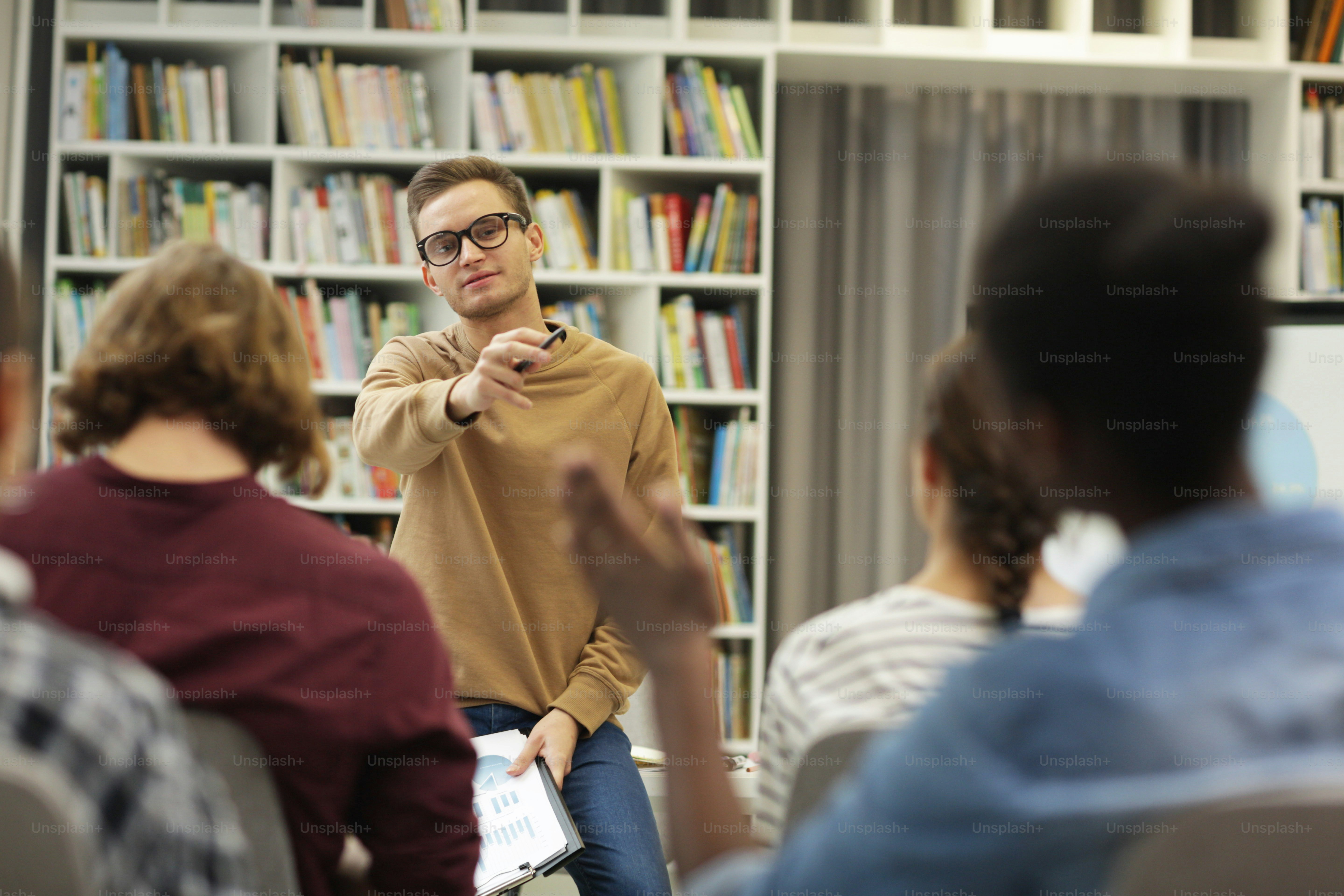 Jeune homme à lunettes pointant vers la jeune femme qui tend sa main et il répond à ses questions pendant la présentation