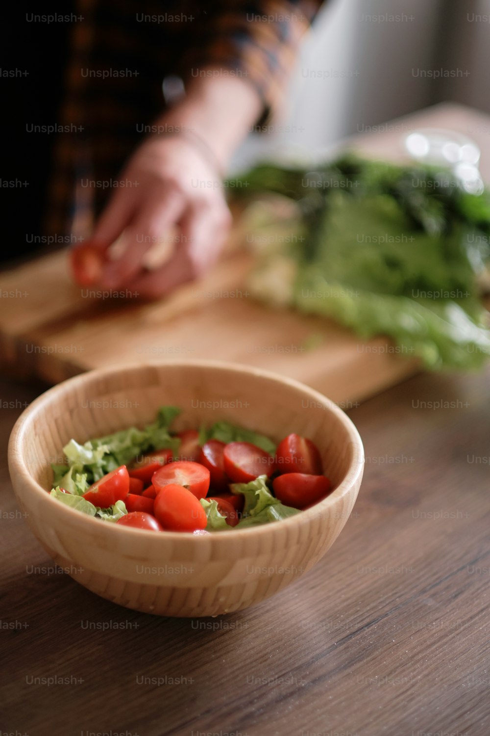 台所で緑のレタスを切る男の手の接写、木製のテーブルでサラダを作る