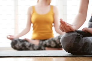 Close up in selective focus of two women hands gesture mudra, while doing yoga vinyasa flow. Front view