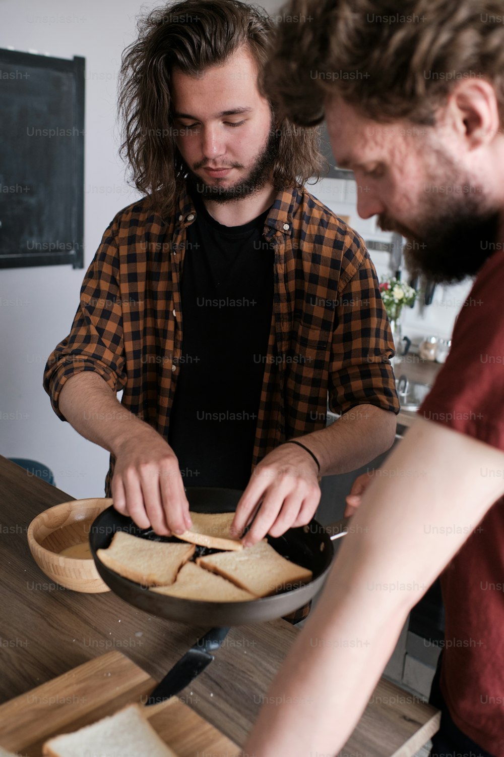 Portrait of two man standing in the kitchen, cooking, making salad. One man is facing camera, another one turned his back
