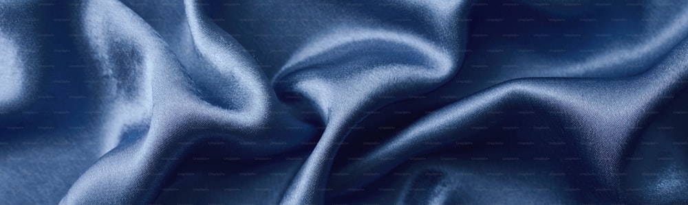 折り目のある銀色の絹の背景。 波打つ絹の表面の抽象的な質感、幅広の長いバナー