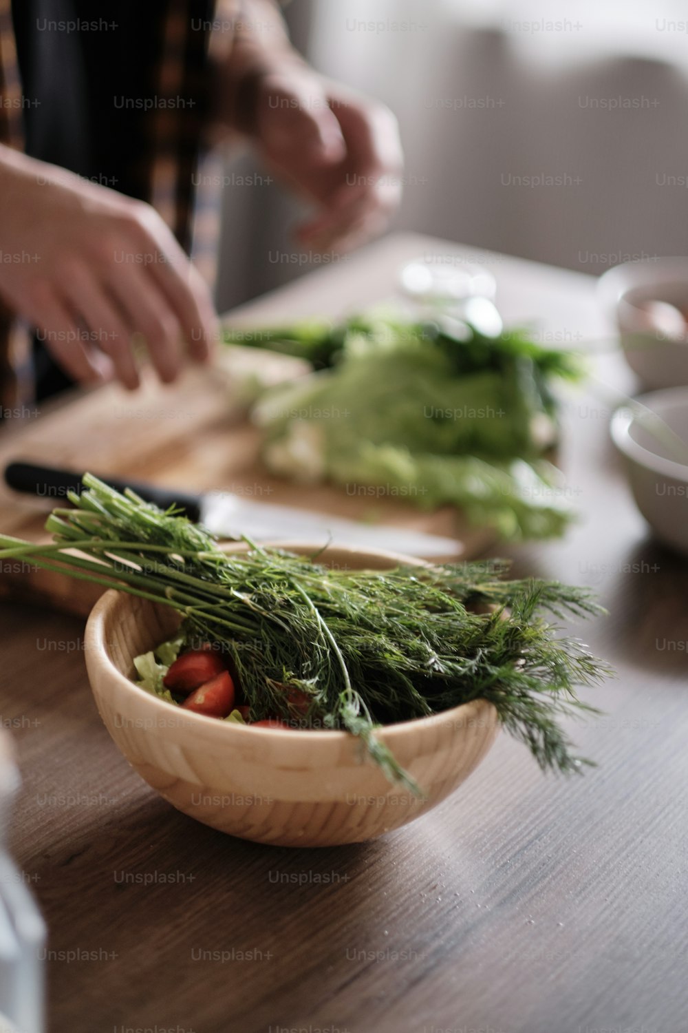 台所で緑のレタスを切る男の手の接写、木製のテーブルでサラダを作る