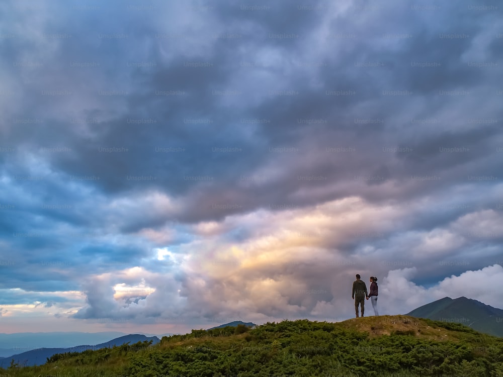 A mulher e o homem de pé na montanha com uma vista pitoresca