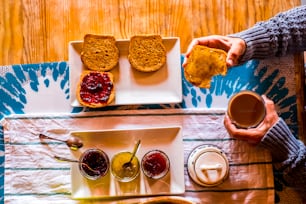 Above view of unrecognizable adult woman having morning breakfast with toasted bread and marmaledes at home or hotel - healthy lifestyle and travel concept people