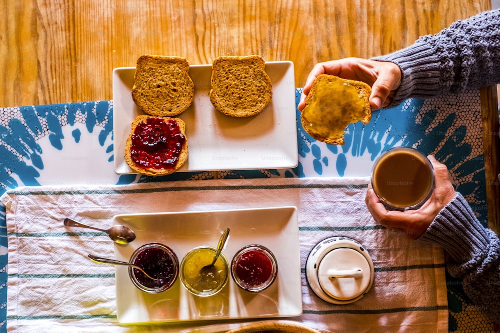 Above view of unrecognizable adult woman having morning breakfast with toasted bread and marmaledes at home or hotel - healthy lifestyle and travel concept people