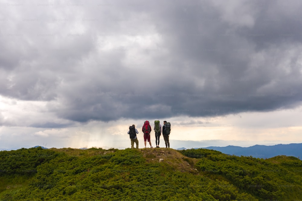 Le quattro persone attive su una montagna contro la pittoresca vista delle nuvole
