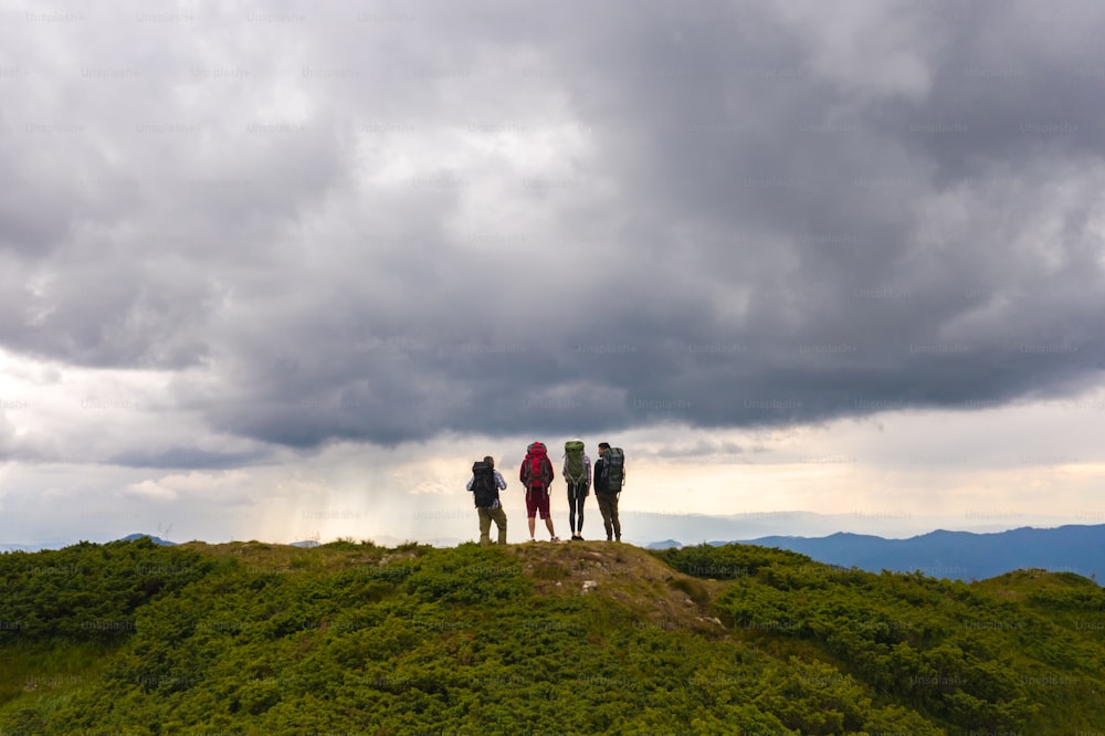 絵のように美しい雲の景色を背景に山の上で活動する4人