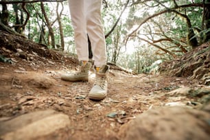 Woman hiking on the forest footpath, close-up view on women's legs in trekking shoes on the dirt road