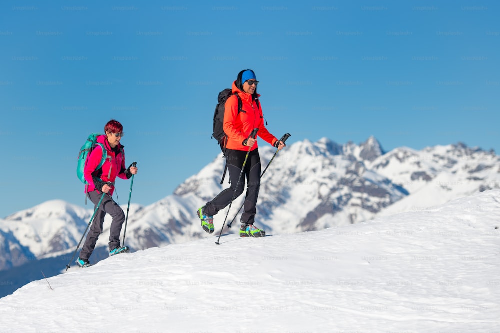 Zwei befreundete Bergsteigerinnen beim Besteigen eines Berges im Winter