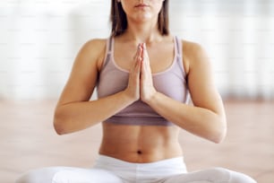 Primo piano di attraente giovane bruna muscolosa seduta in posizione di loto e meditazione.