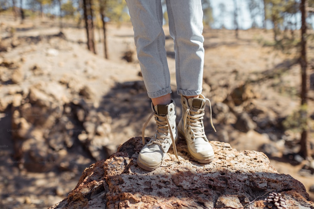 Mujer de pie sobre las piedras, caminando en una tierra rocosa, primer plano en las piernas en zapatos de trekking