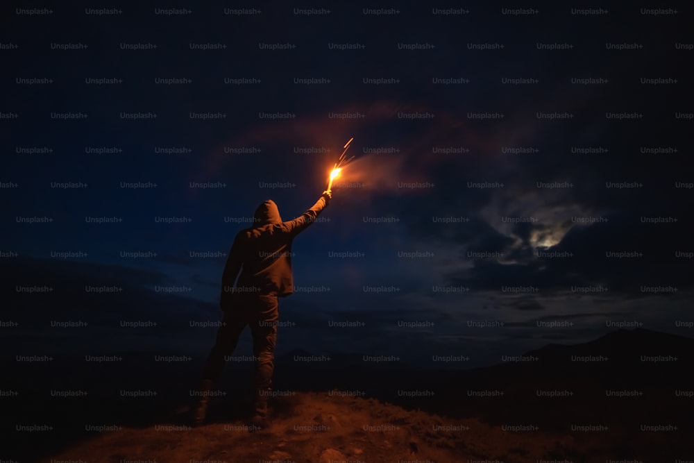 The male with a firework stick standing on the night mountain