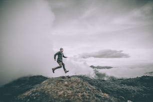 O homem que pula na montanha em um belo fundo de nuvens