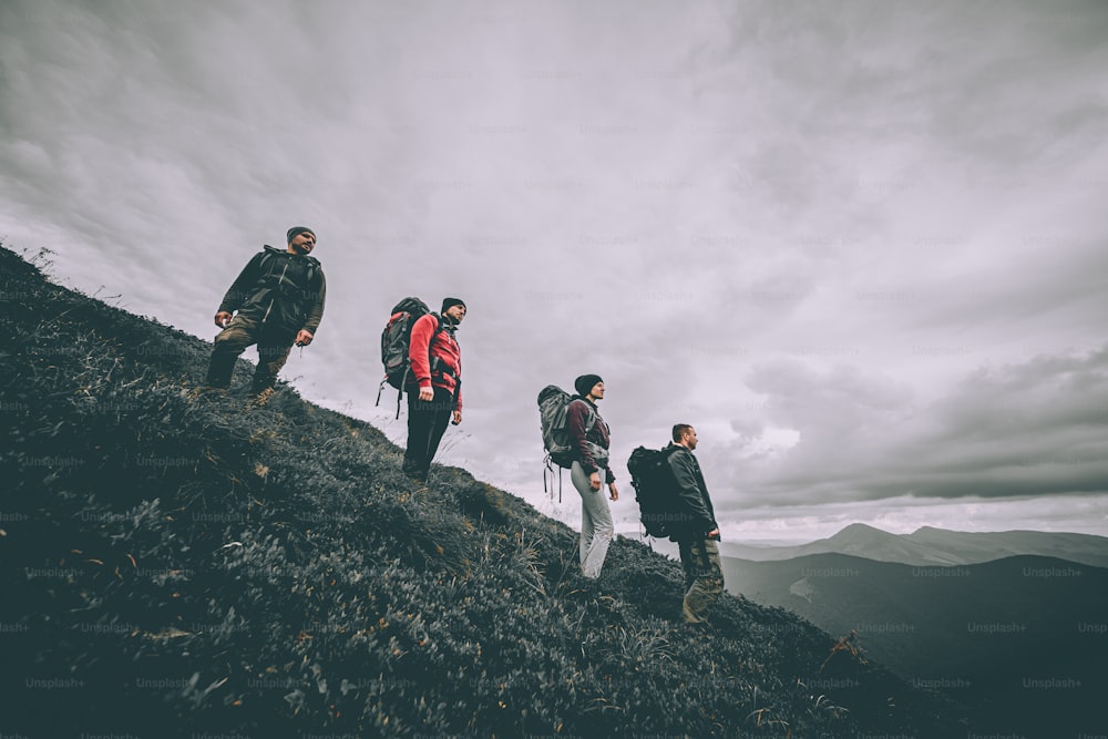 Les quatre personnes avec des sacs à dos debout sur la montagne