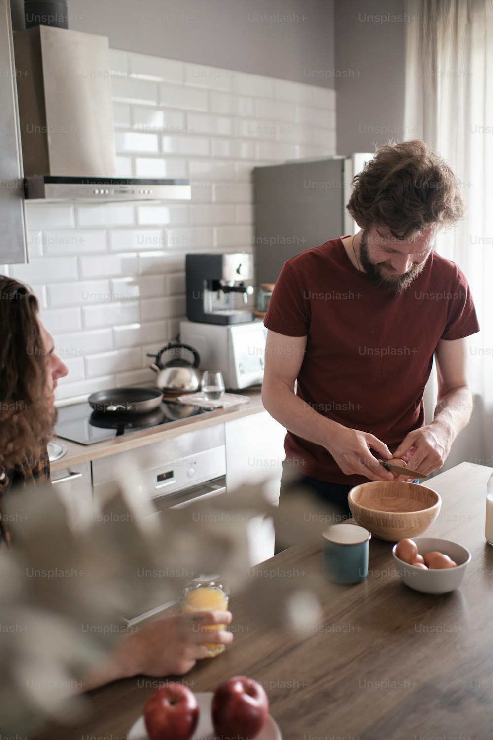 Retrato de dos hombres conversando en la cocina mientras uno prepara el desayuno