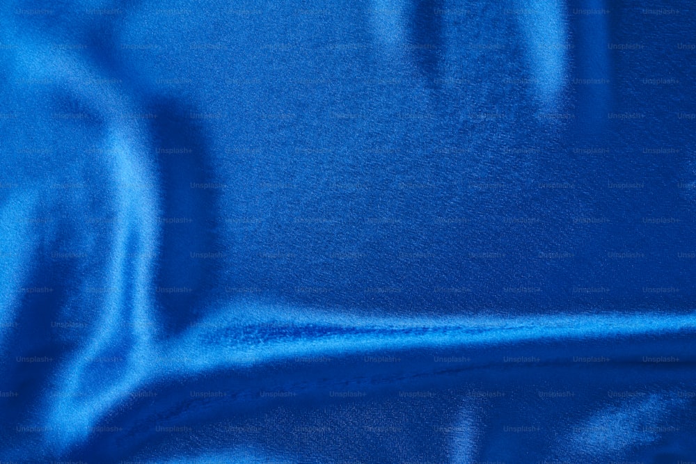 Blue silk background with folds.  Abstract texture of rippled satin surface