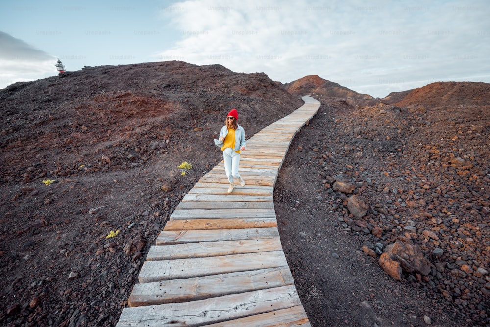 Woman running on the beautiful boardwalk through the volcanic land, enjoying a trip on the island