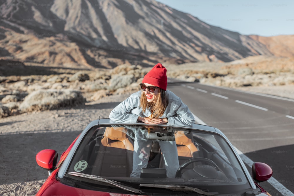 사막 계곡에서 도로 여행을 즐기는 젊은 여성의 라이프스타일 초상화, 길가에 있는 컨버터블 차에서 내리다