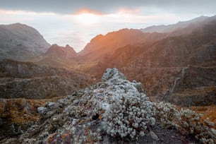 Des paysages à couper le souffle sur la chaîne de montagnes sous les nuages et l’océan en arrière-plan lors d’un coucher de soleil