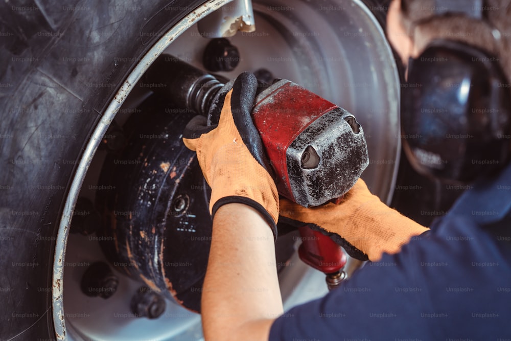 Close-up of farm machine mechanic working on wheel with power tool