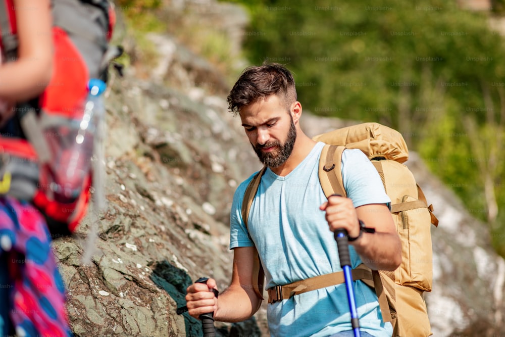 Hikers with backpacks and hiking sticks clim the mountain.