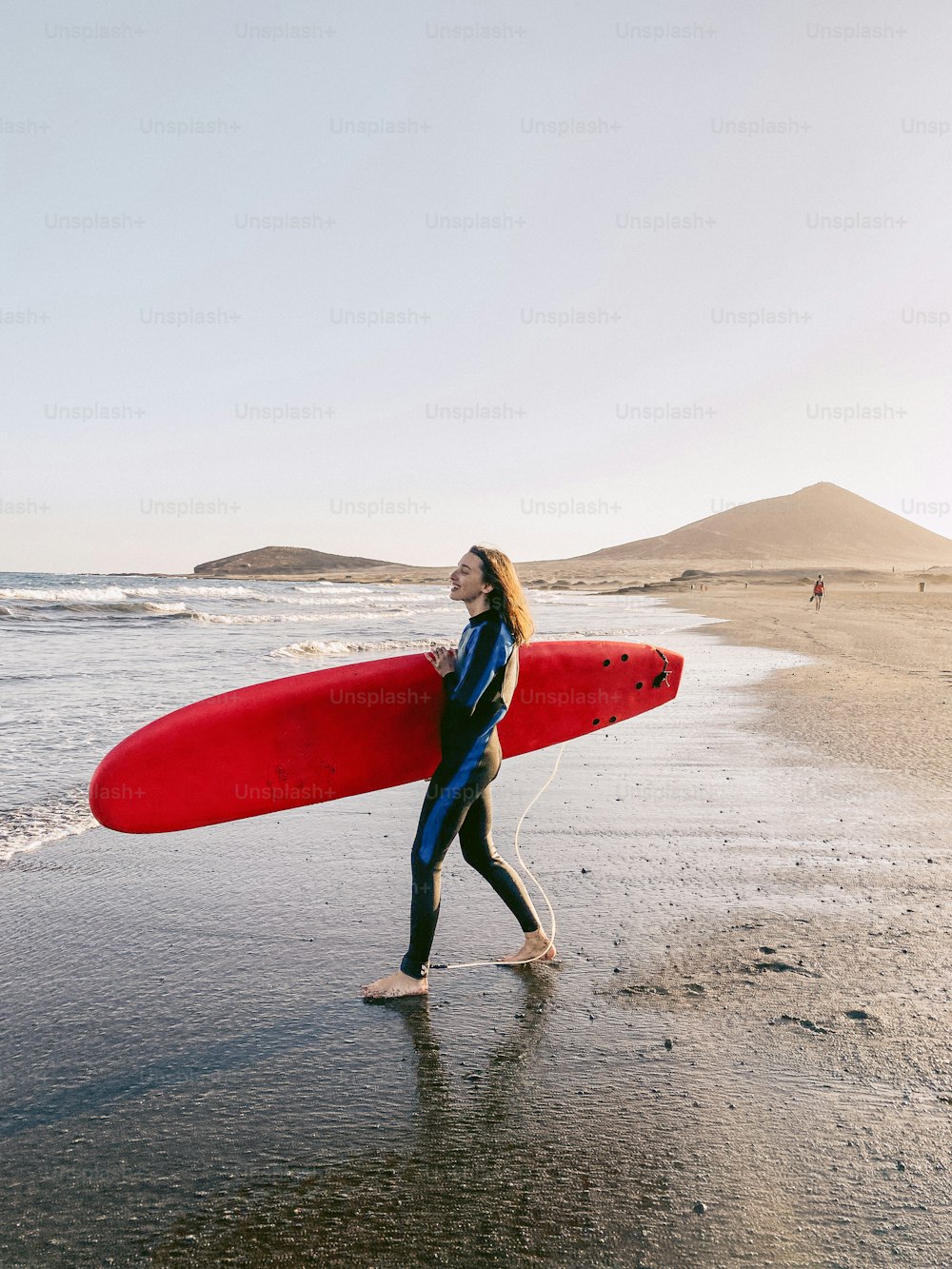 해변에서 서핑보드와 함께 걷는 젊은 서퍼. 휴대 전화에서 만든 이미지