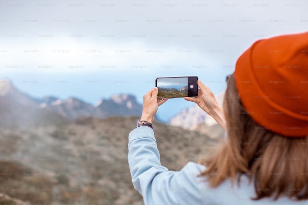 Mujer fotografiando en el teléfono hermosos paisajes, viajando muy alto en las montañas de la isla de Tenerife