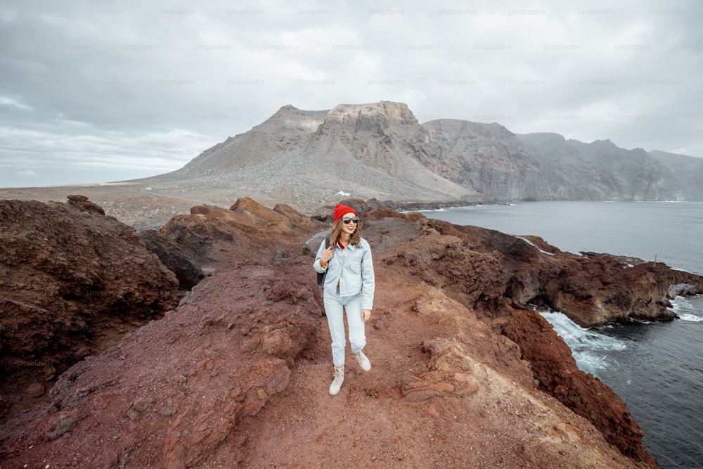 Joven viajero caminando en la orilla rocosa del océano, hermosa vista del paisaje en la isla de Tenerife, España. Concepto de viaje y aventuras sin preocupaciones