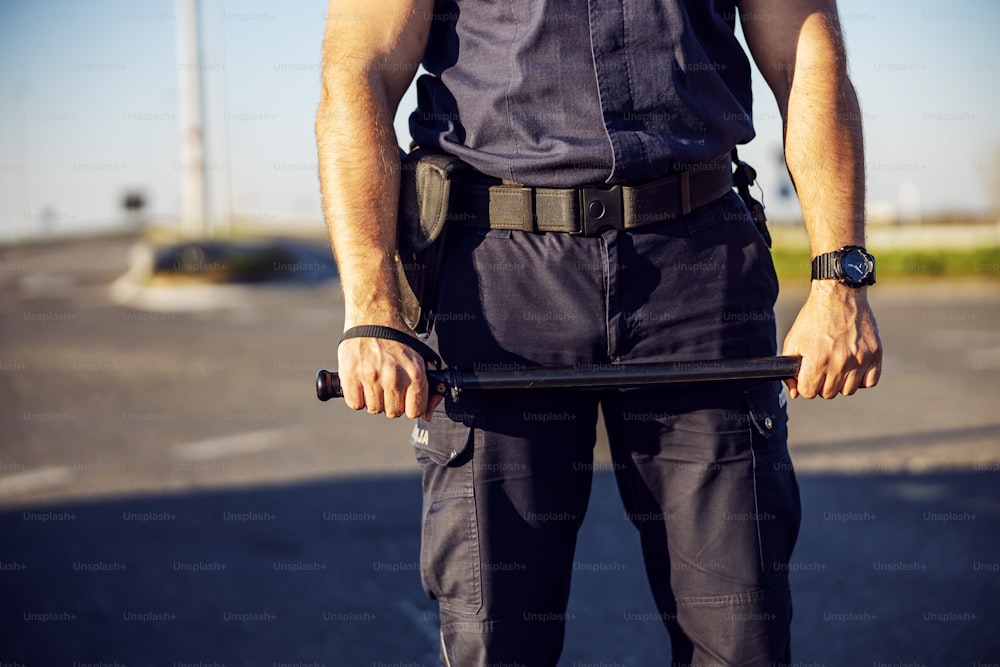 Police officer baton in hands. Policeman in action.