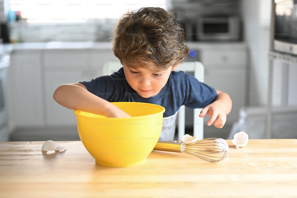a young boy mixing something in a yellow bowl