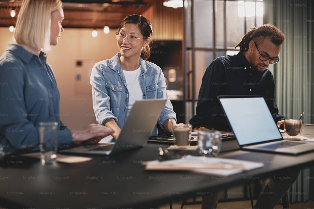 Diverse group of young businesspeople talking together while working at a table in an office