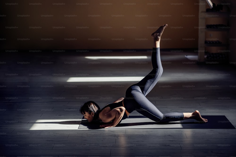 Jeune femme yogi attrayante se préparant à la pose de yoga du menton. Intérieur du studio de yoga.