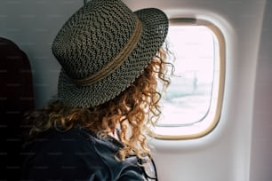 Woman travel on aircraft flight - fly for business or holiday vacation people inside airplane looking outside from the window - concept of transport and freedom