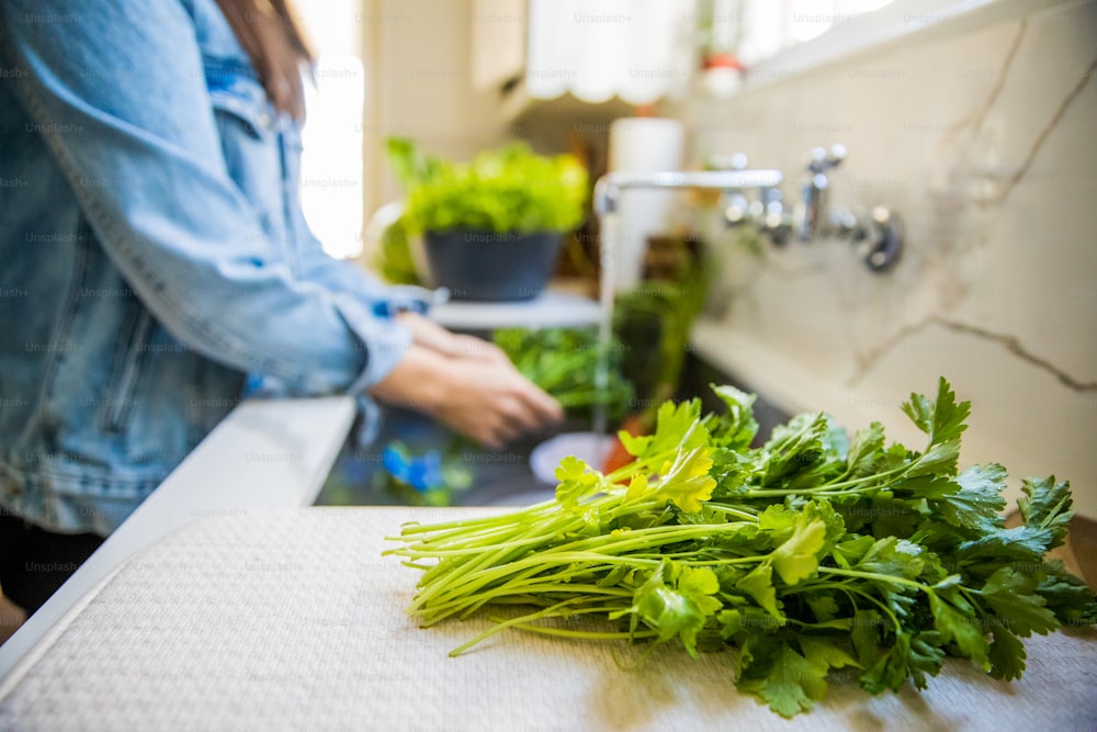 Woman washing and drying fresh vegetables in sink