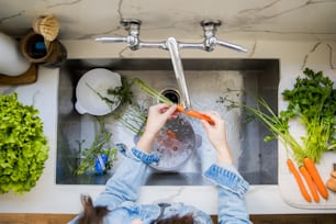 Mujer lavando verduras frescas en el fregadero