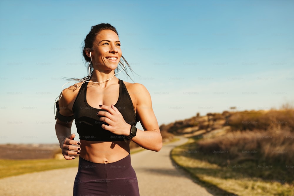 Young happy fitness instructor jogging in nature. Copy space.